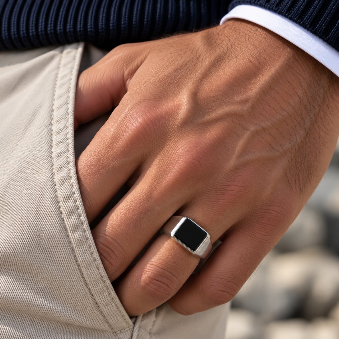 Mann trägt den Rico's Siegelring aus Stahl mit schwarzem Onyx am Ringfinger, die Hand in der Hosentasche